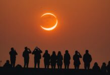 Éclipse solaire du 12 août : comment l’observer en toute sécurité depuis la France Éclipse solaire partielle en forme de croissant dans un ciel orange au-dessus d'une skyline européenne
