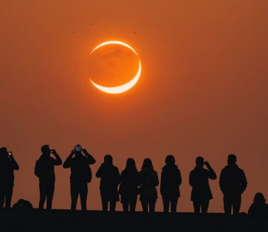 Éclipse solaire du 12 août : comment l’observer en toute sécurité depuis la France Éclipse solaire partielle en forme de croissant dans un ciel orange au-dessus d'une skyline européenne